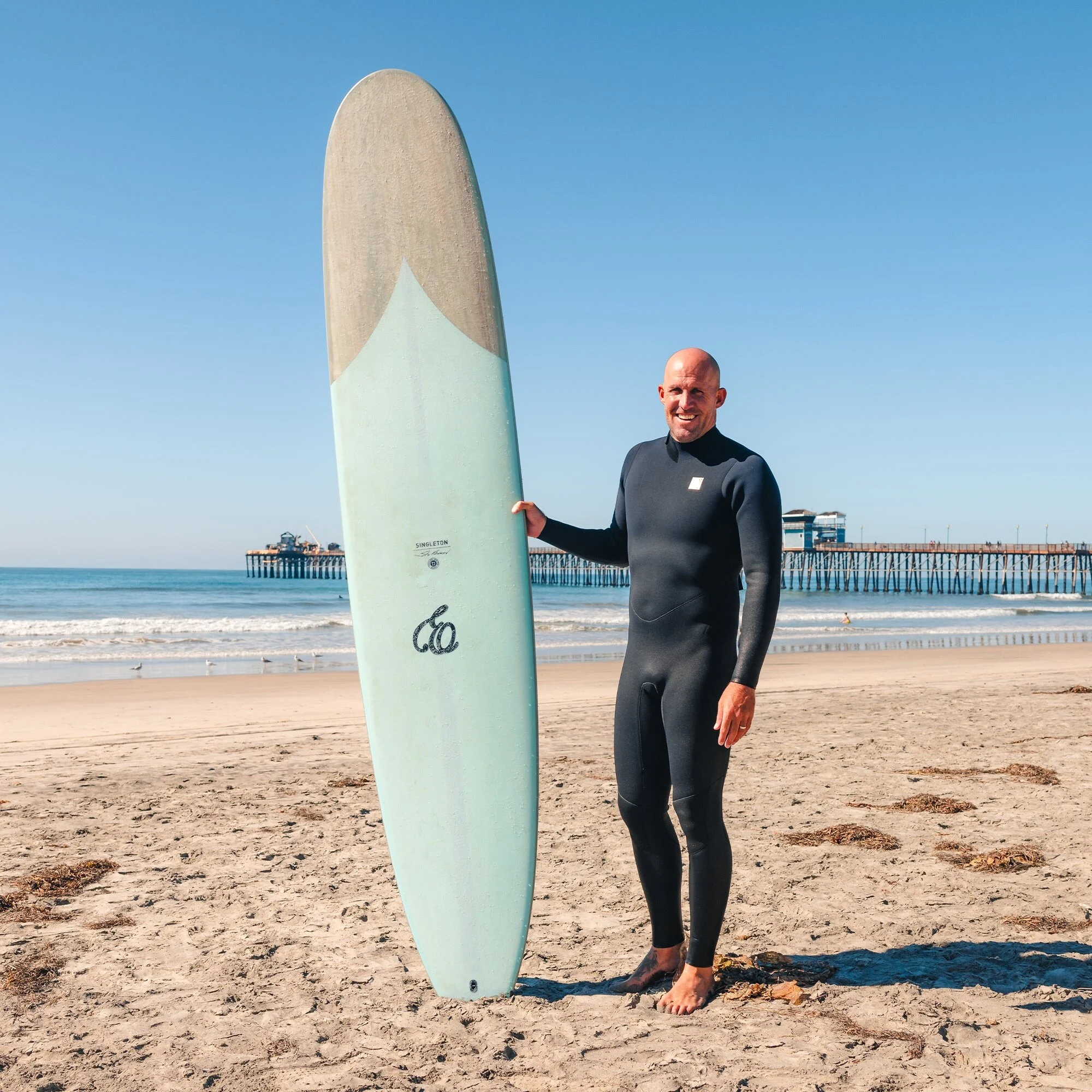 Kelly Slater na praia com um longboard Firewire