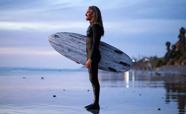 Rob Machado na praia ao entardecer com uma prancha Firewire